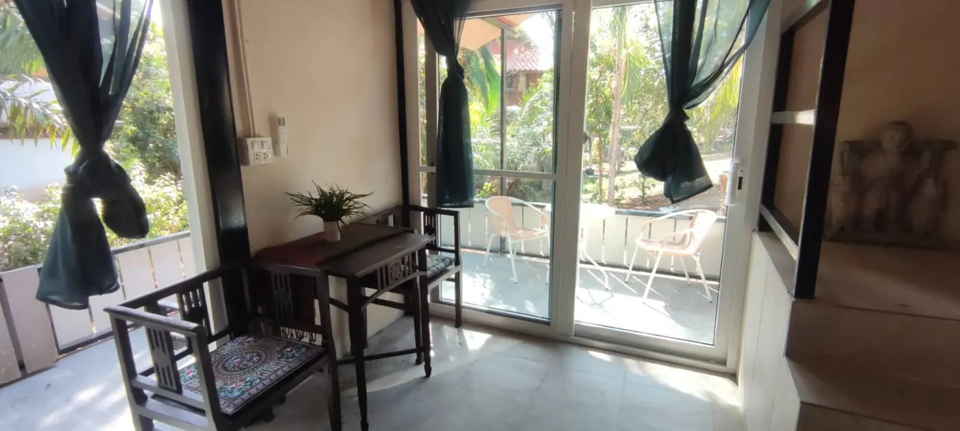 Terrace sitting area with Thai wooden chairs and balcony overlooking the garden at Rambutan House, Koh Mak