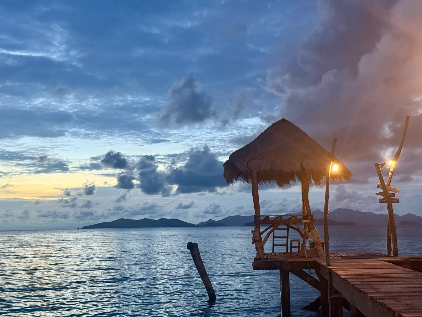 Golden sunset over the sea viewed from the thatched-roof pier sala at Cococape Resort, Koh Mak, Thailand