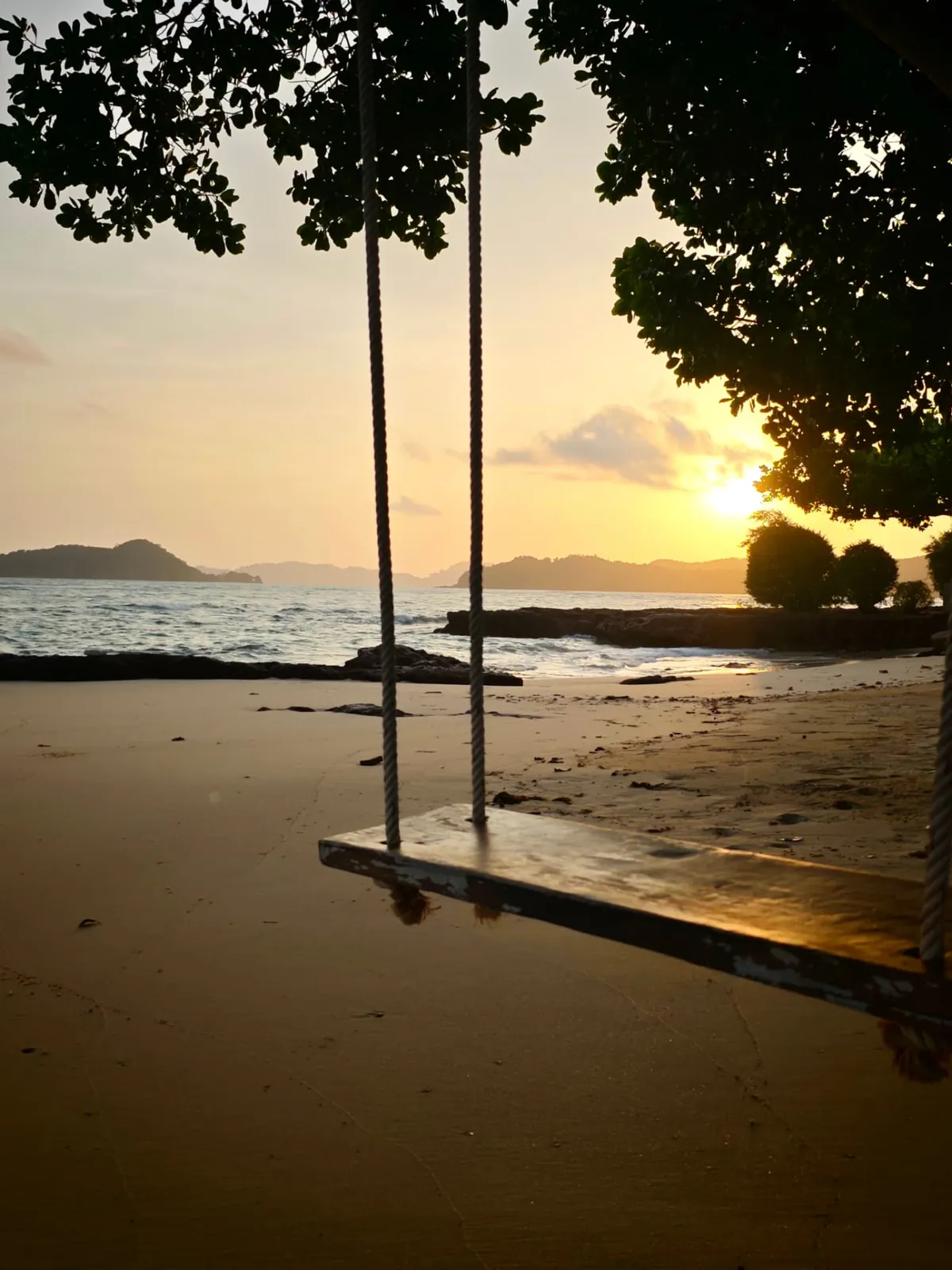 Wooden swing on a sandy Koh Mak beach at golden sunset