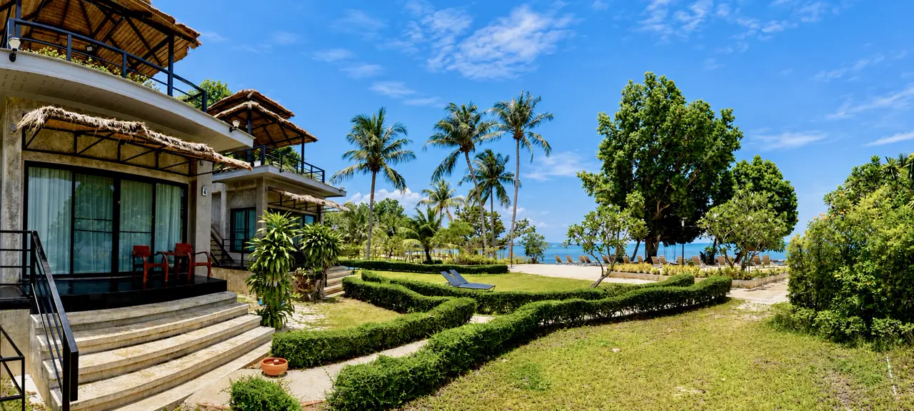 Beachfront villas at White Sand Beach Resort with manicured gardens, palms and sun loungers by the sea