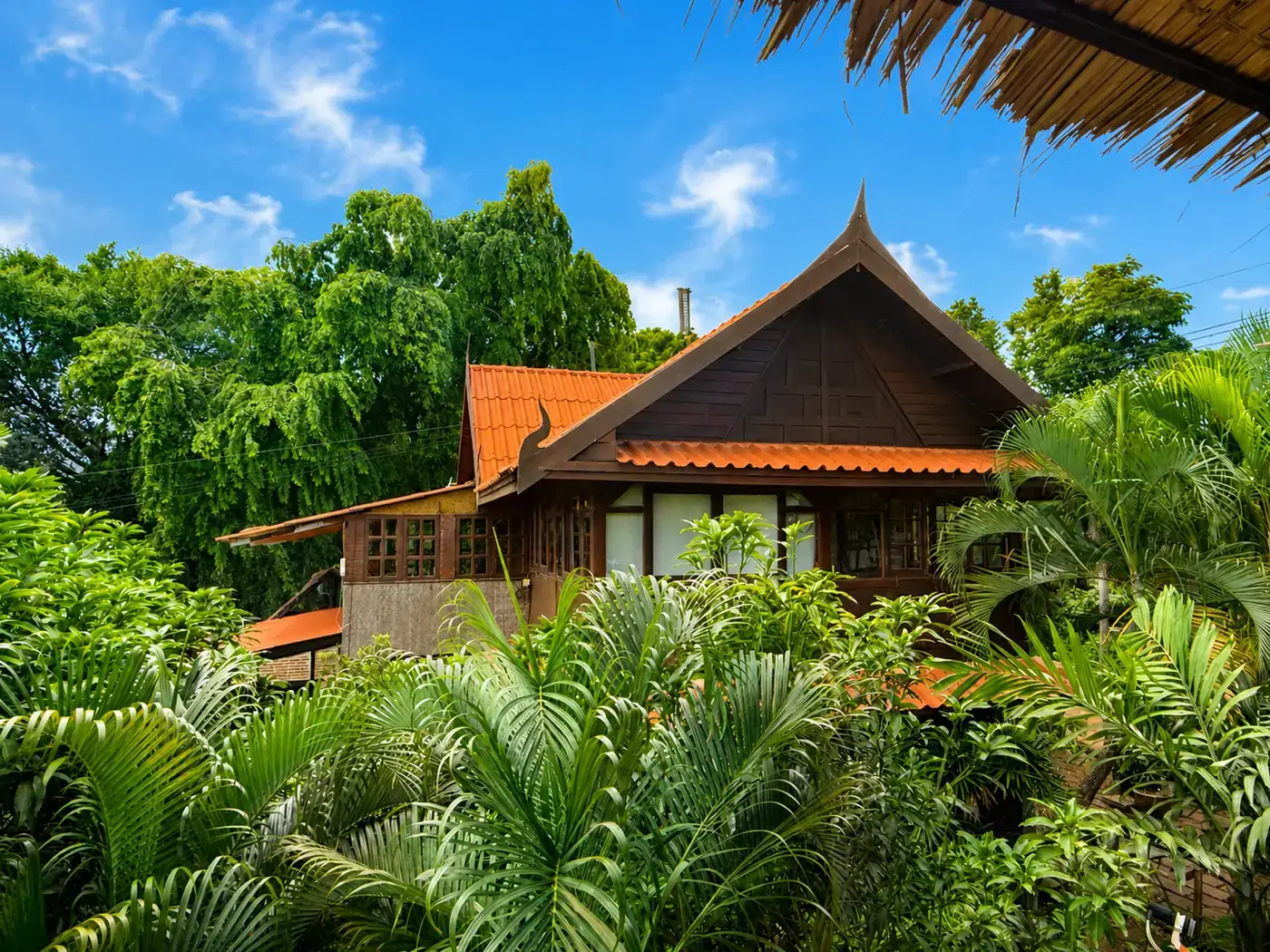 Traditional Thai-style house with orange tiled roof surrounded by palms — Seaview Suites Upstairs at Koh Mak Village