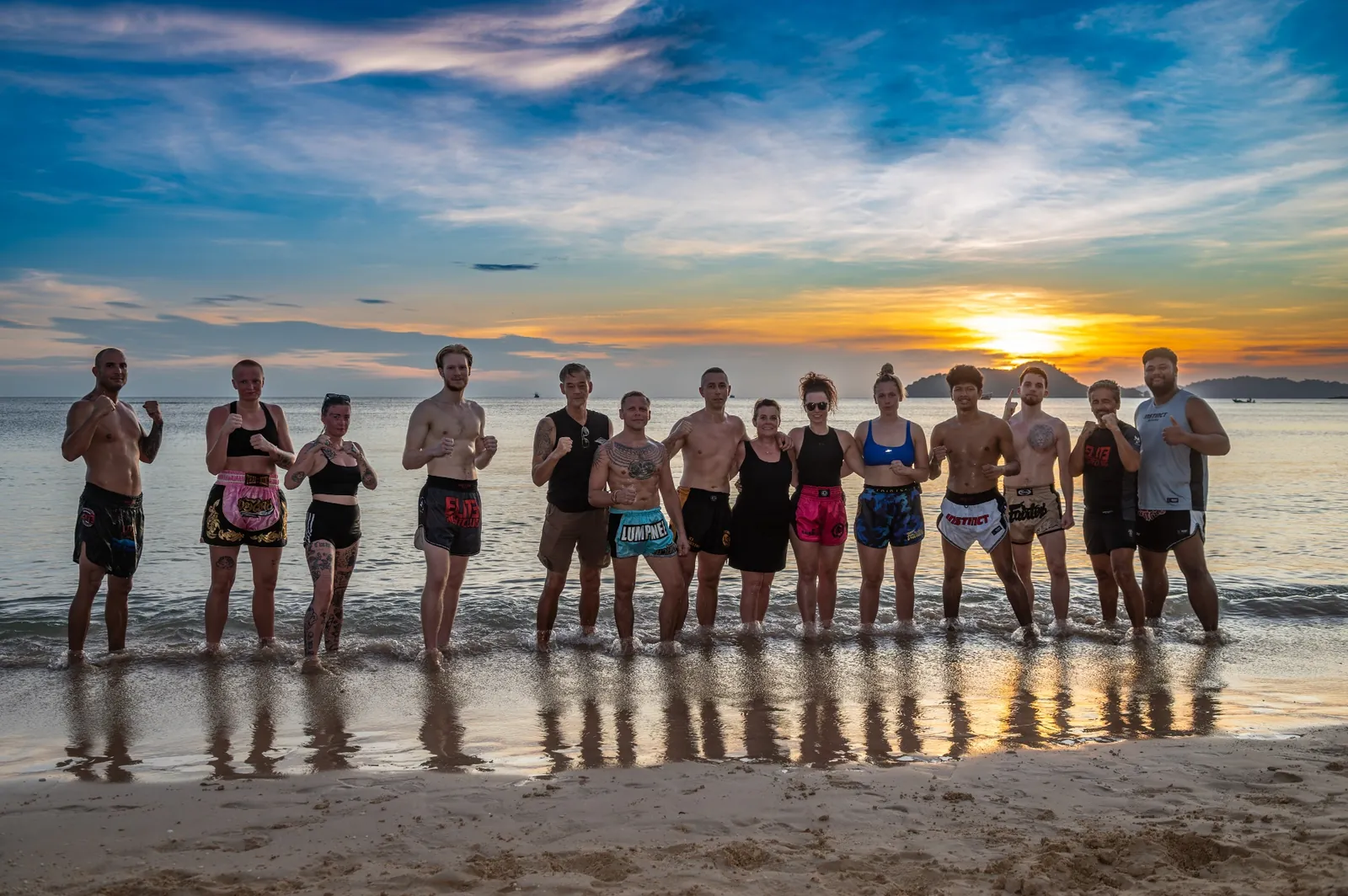 Muay Thai group standing in the shallows at sunset on Koh Mak beach