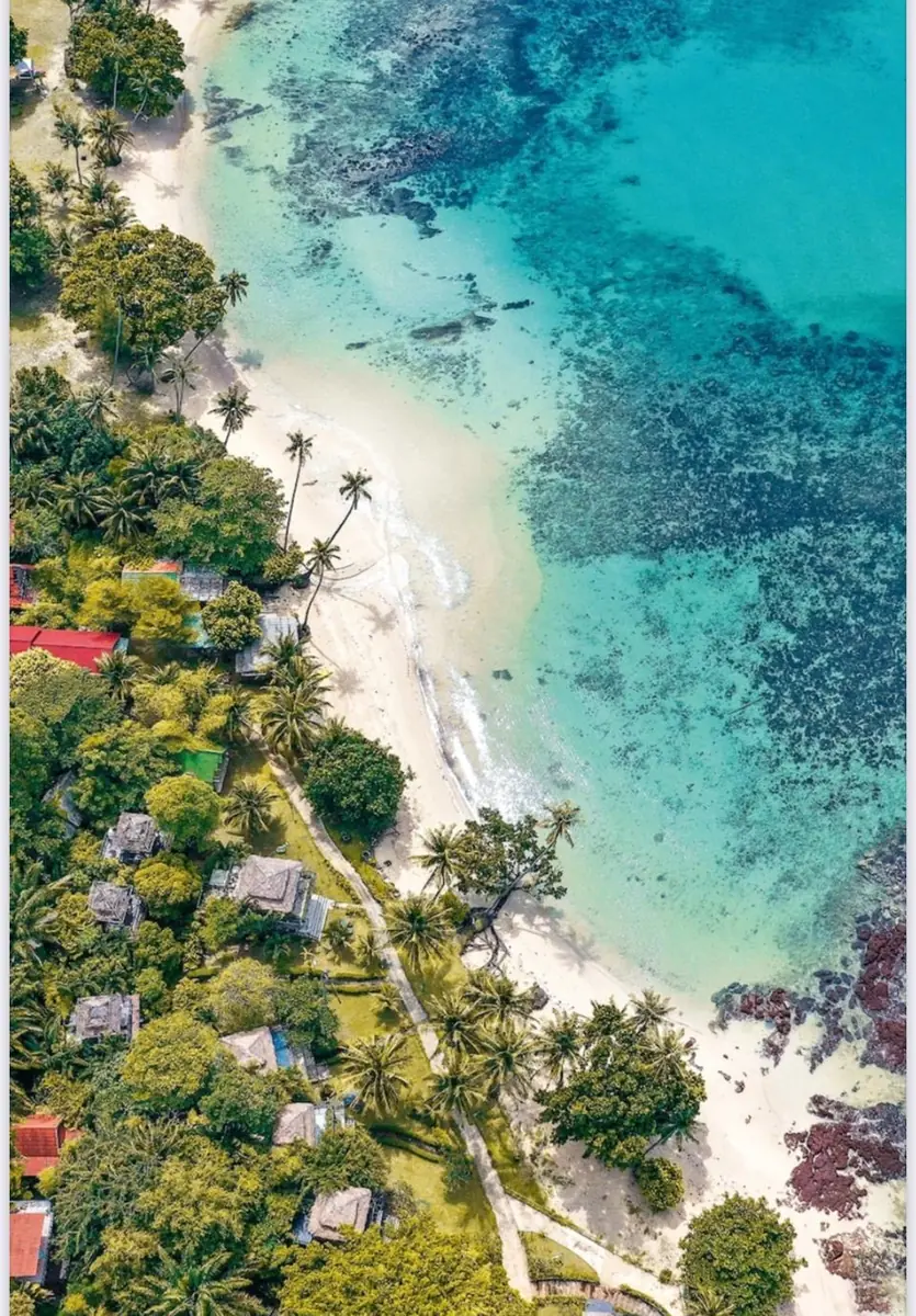 Aerial view of a turquoise bay, sandy beach and palm trees on Koh Mak