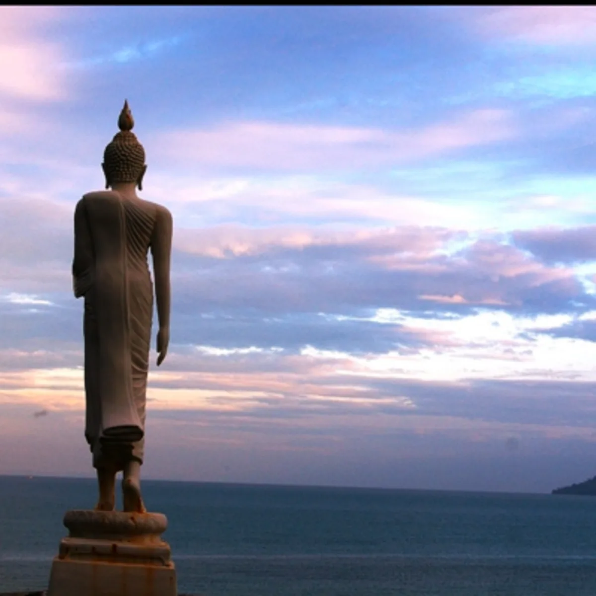 Standing Buddha statue overlooking the sea at sunset on Koh Mak
