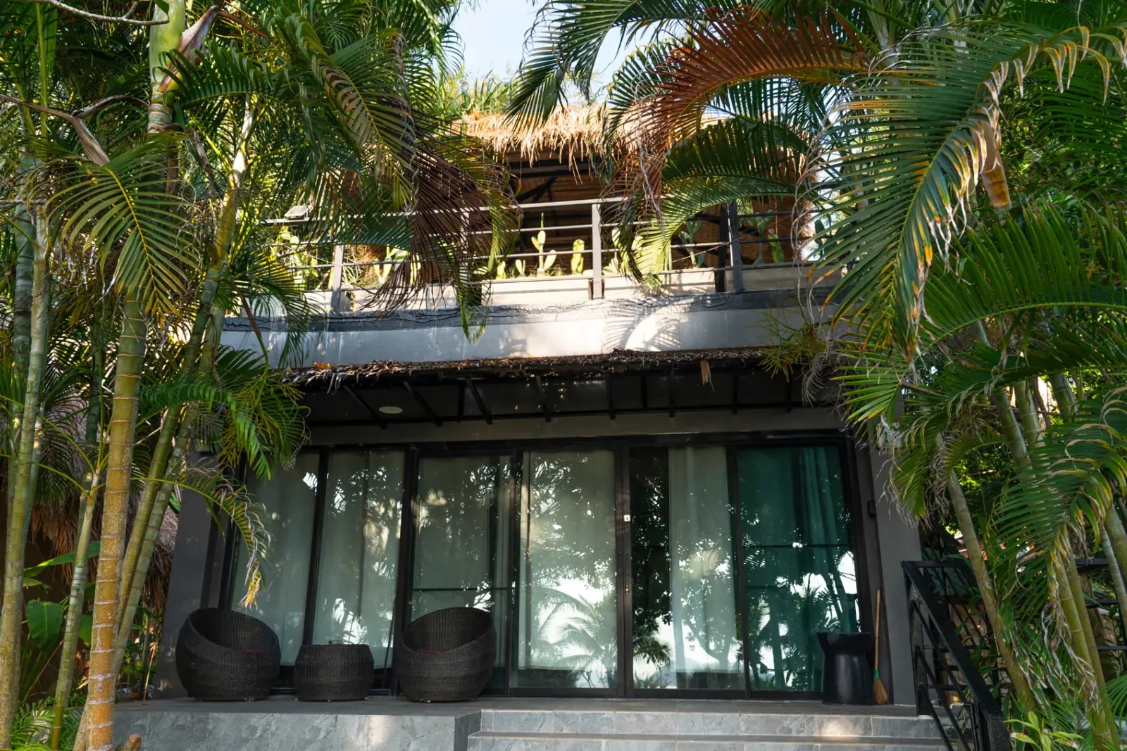 Private Beachfront Villa exterior on Koh Mak — thatched-roof villa with rooftop terrace framed by palms and bamboo