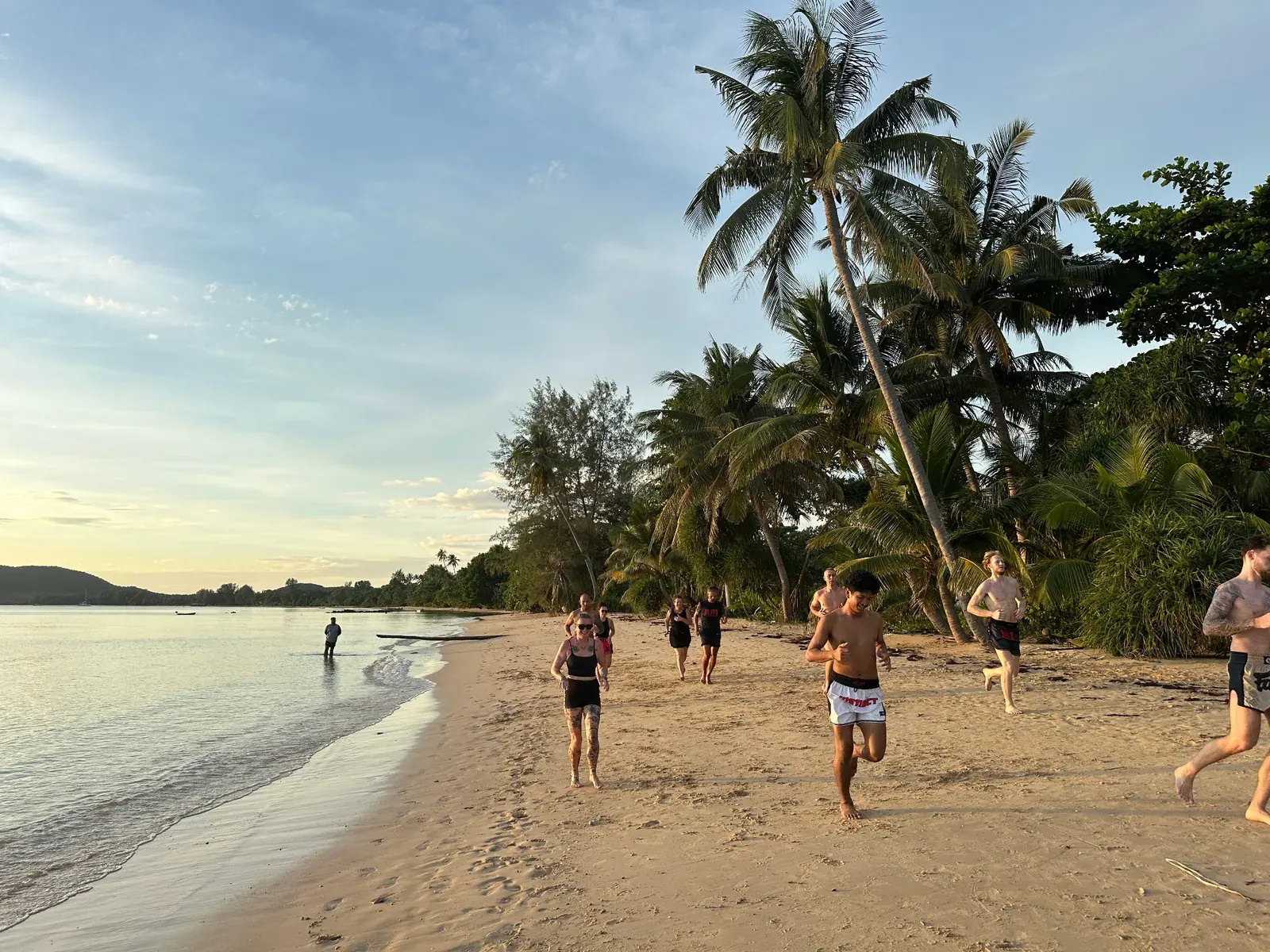 Group running along the beach at sunset on Koh Mak