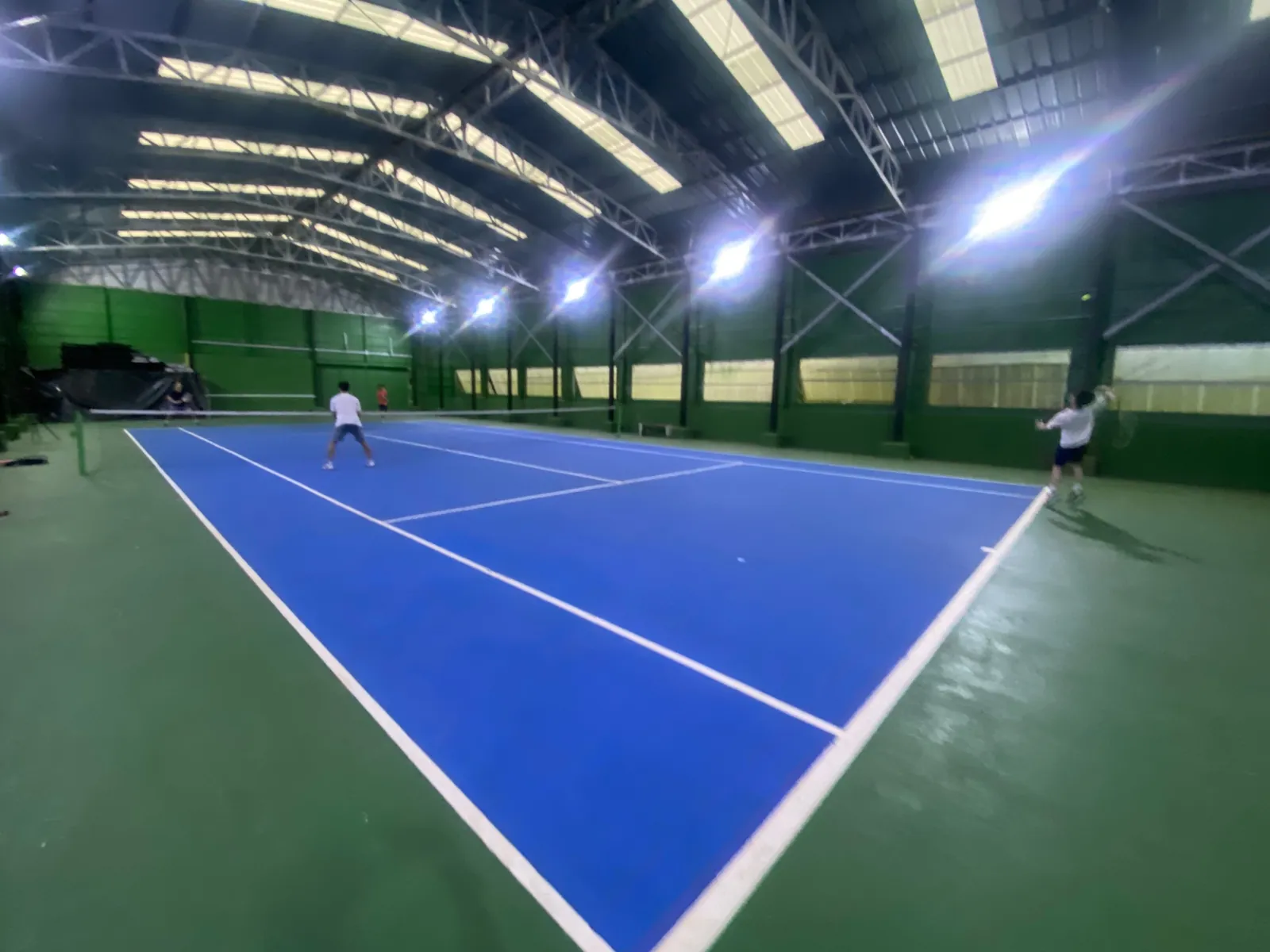 Players rallying on the indoor tennis court at White Sand Beach Resort, Koh Mak
