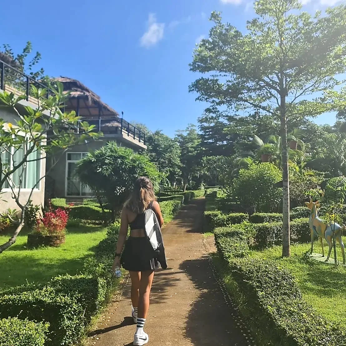 Player walking through a lush tropical garden path to the tennis courts on Koh Mak