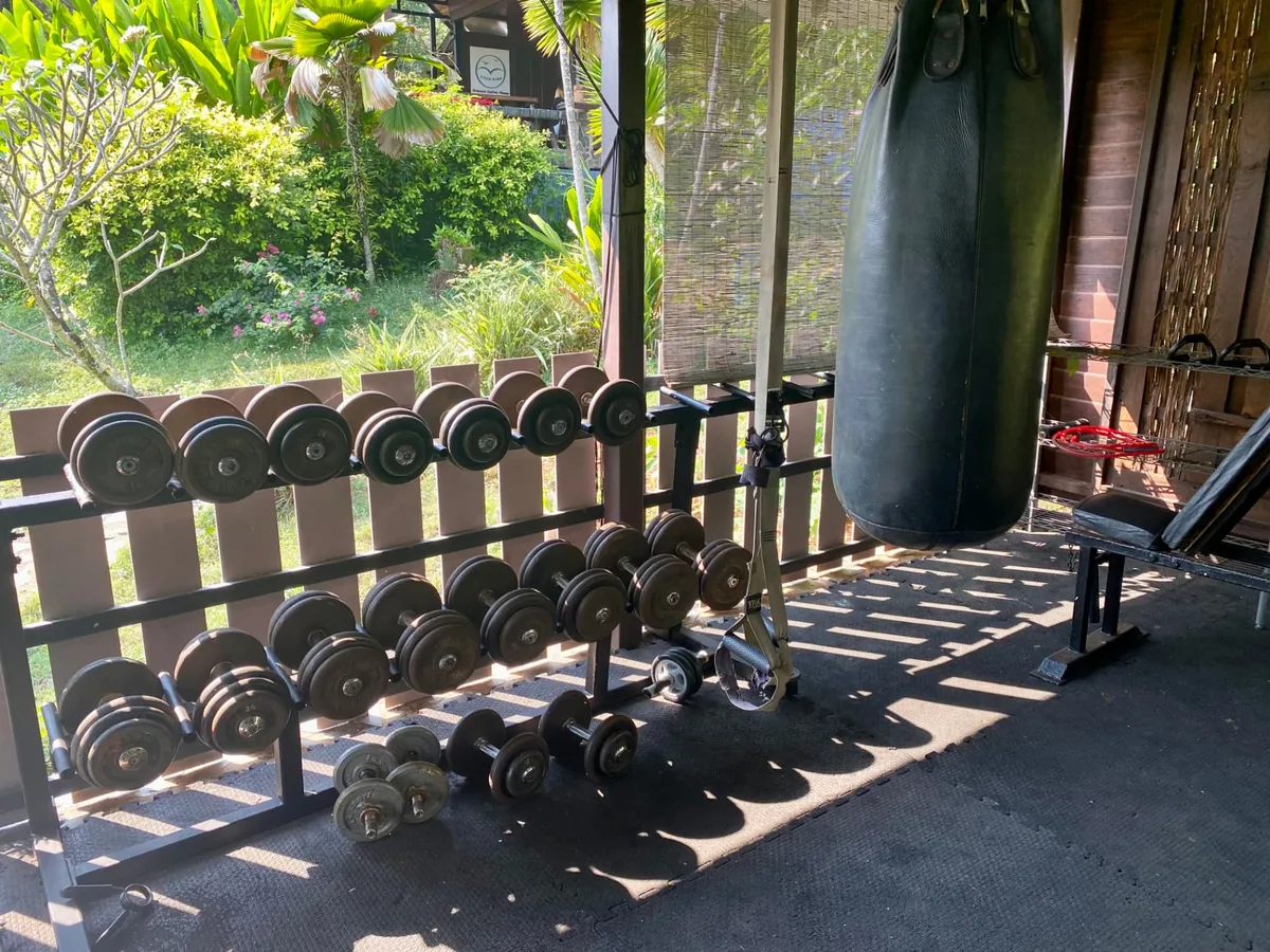 Dumbbell rack and punching bag in the open-air Phoenix Gym on Koh Mak