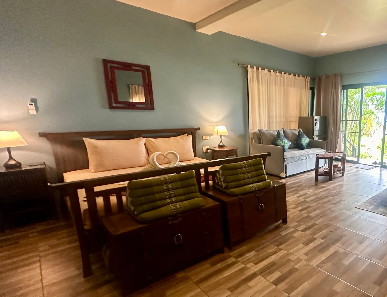 Living room and bedroom of the Owners Beachfront Villa with wooden bed, sofa and garden view, Koh Mak, Thailand