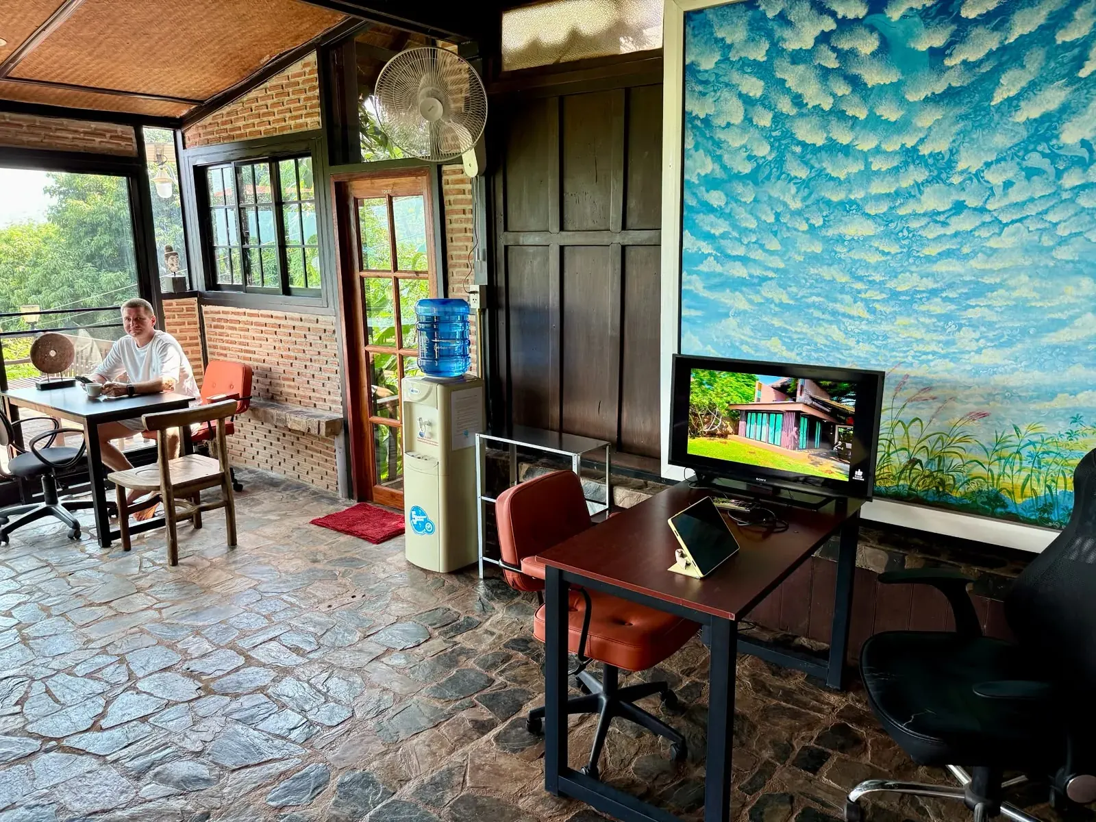 Co-working space on Koh Mak with desks, fan and cloud mural