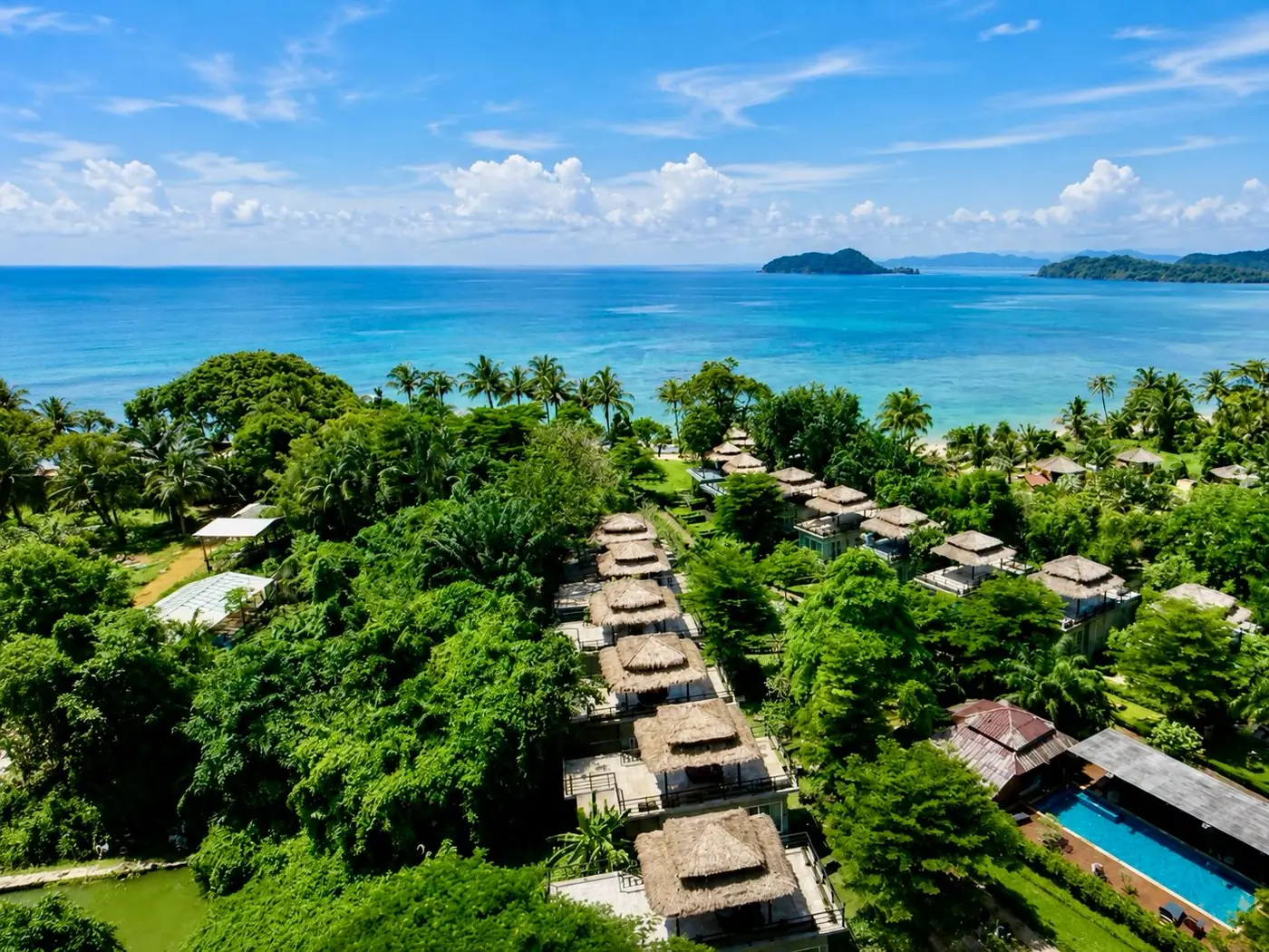 Aerial view of White Sand Beach Resort villas lined among palms with turquoise sea and pool on Ao Kao, Koh Mak