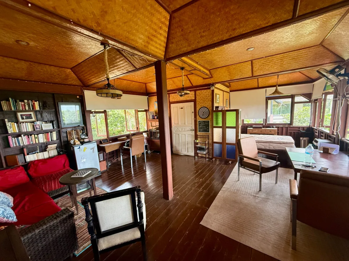 Spacious open-plan lounge of the Upstairs seaview suite with wooden ceilings, red sofas, bookshelves, desk and sea-view windows on Koh Mak