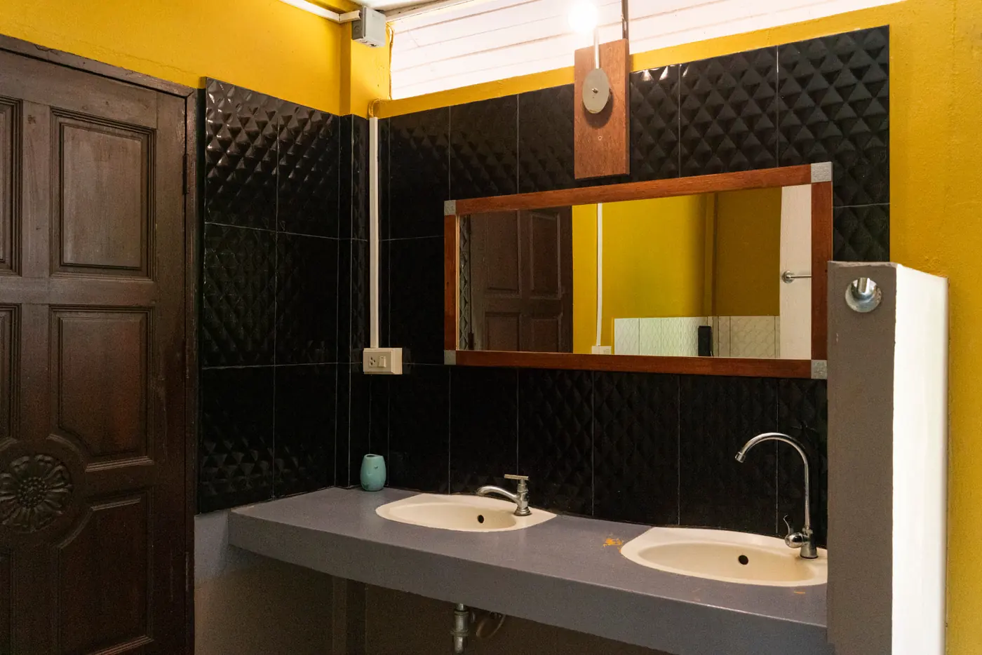 Spacious bathroom with double sinks, black tiles and yellow walls at Rambutan House, Koh Mak