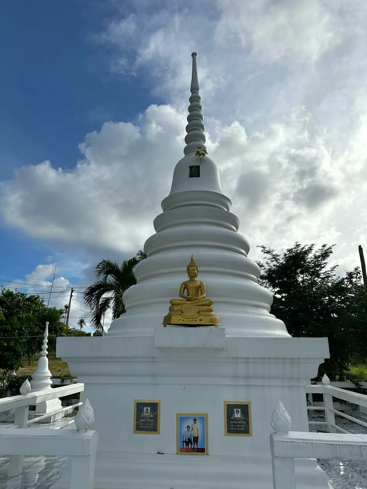 Whitewashed Buddhist stupa with a small golden Buddha statue at Wat Koh Mak