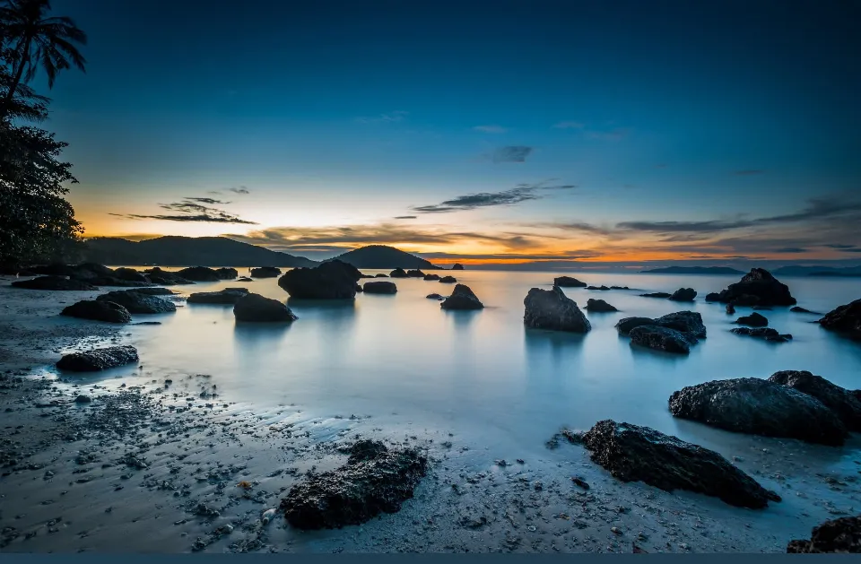 Rocky shoreline and calm sea at blue-hour sunset on Koh Mak