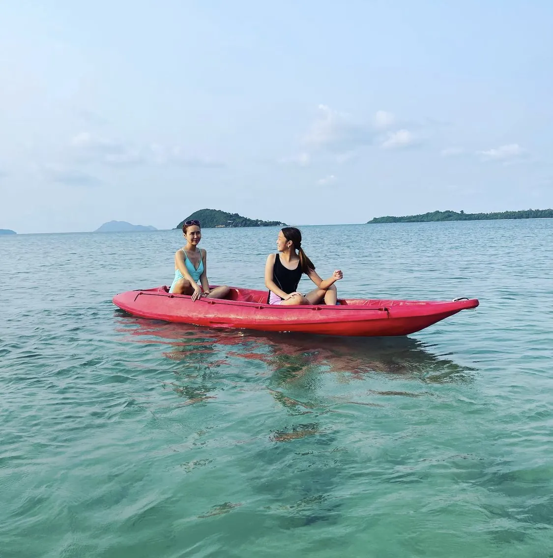 Two friends kayaking on calm clear water off Koh Mak