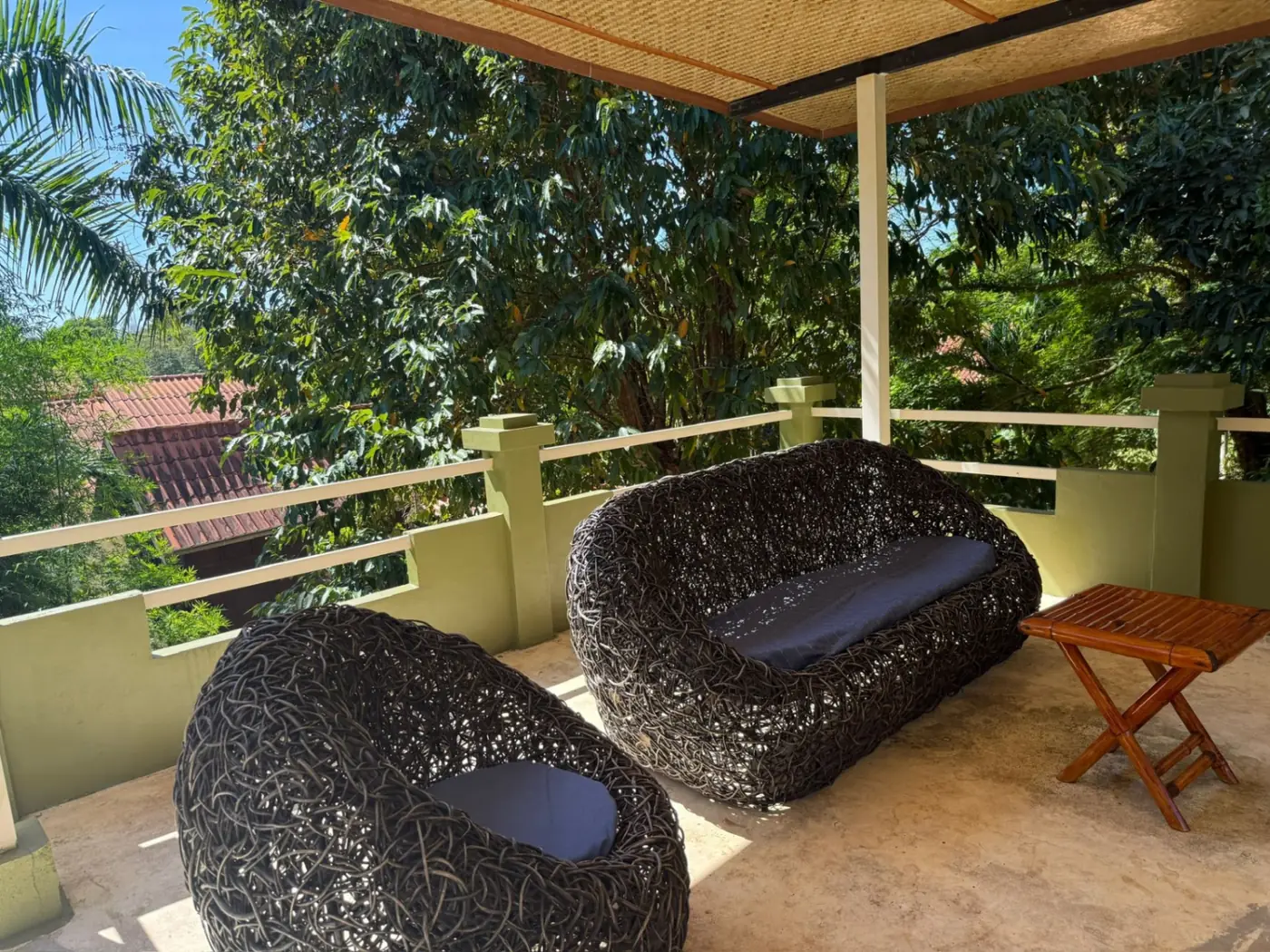 Upper terrace with rattan sofas overlooking the tropical garden at Sugarcane Villa, Koh Mak