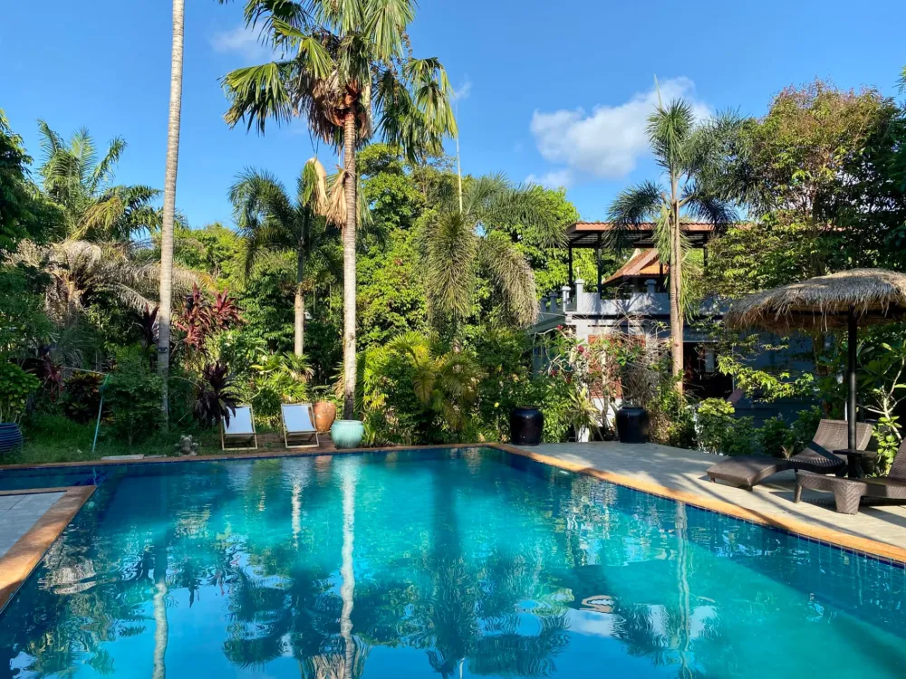 Tropical resort swimming pool surrounded by palm trees on Koh Mak