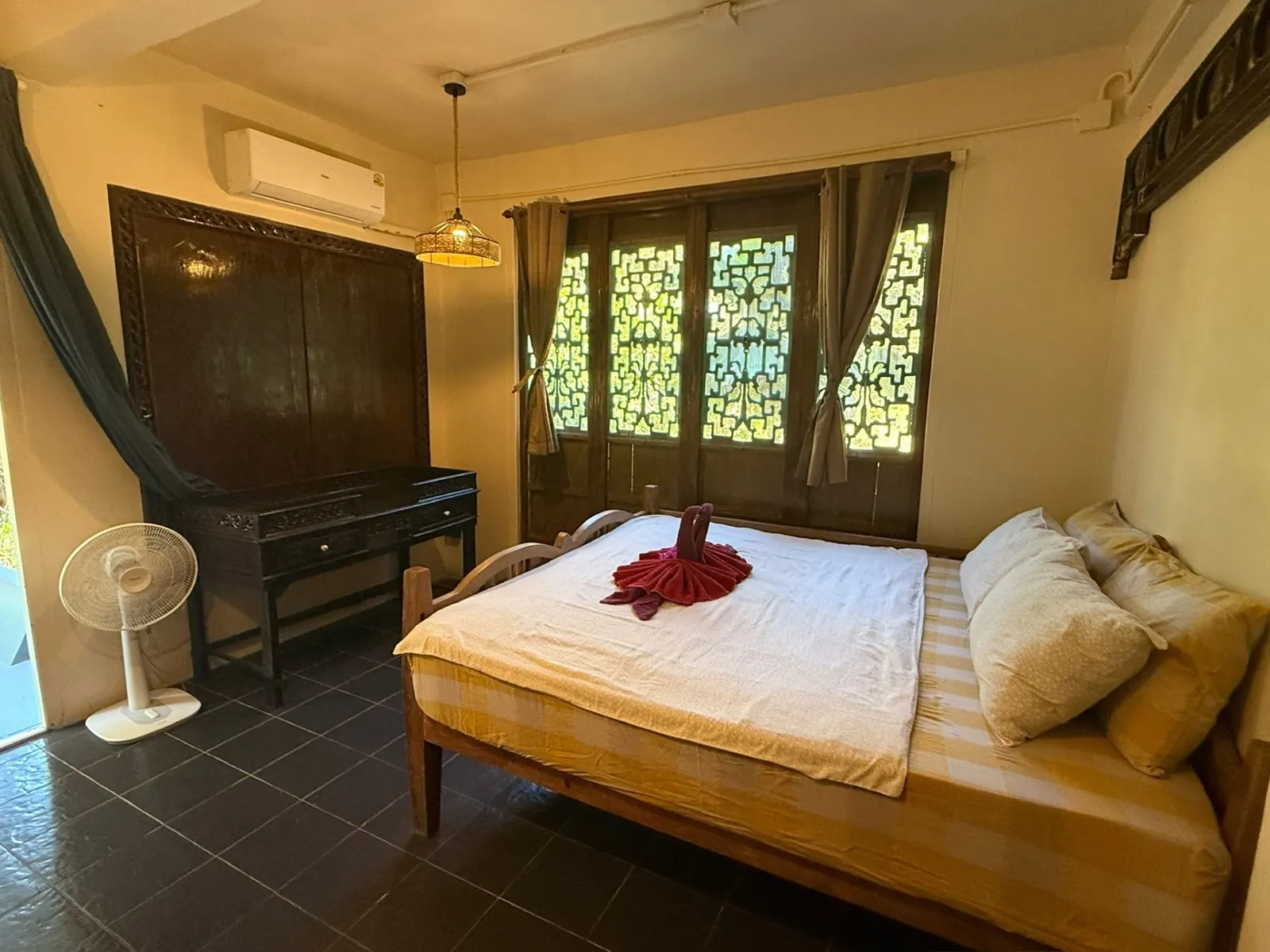 Master bedroom with carved Thai headboard, AC and king bed at Sugarcane Villa, Koh Mak