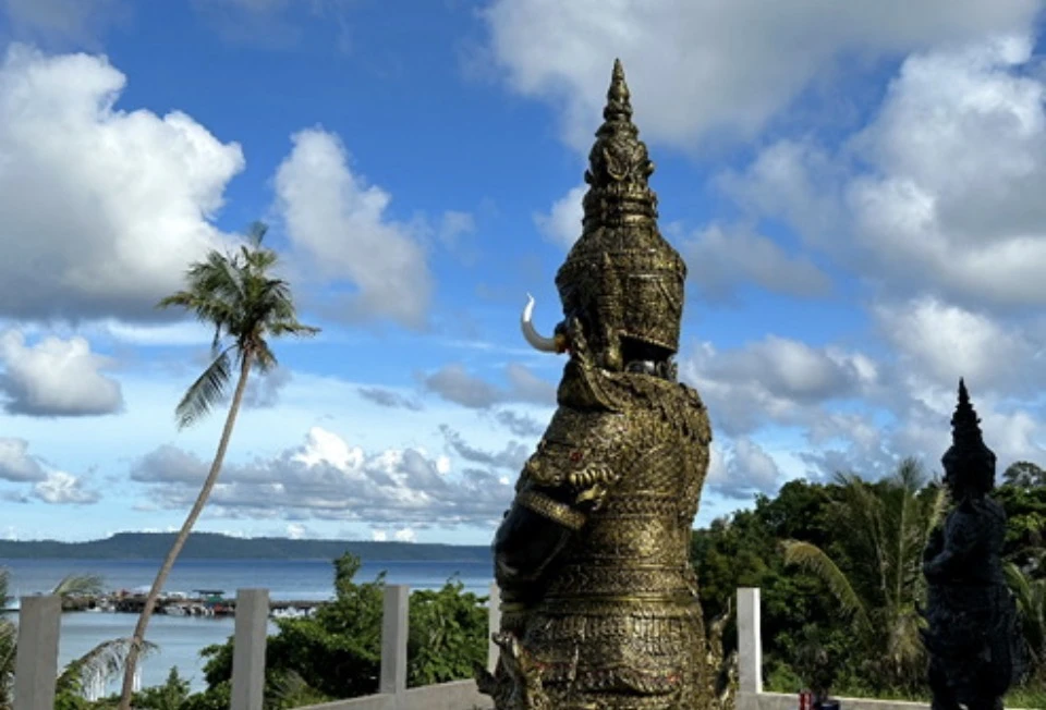 Ornate golden temple guardian statue overlooking the sea on Koh Mak