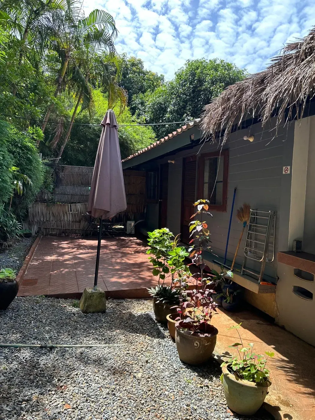 Koh Mak Hostel Hammock single room exterior with thatched roof, umbrella and tropical plants on Koh Mak, Thailand