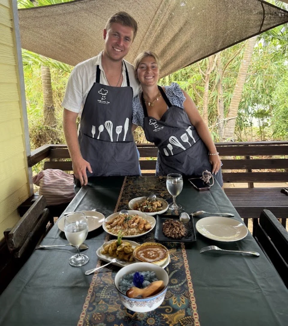 Two people in aprons with Thai dishes prepared during a cooking class on Koh Mak