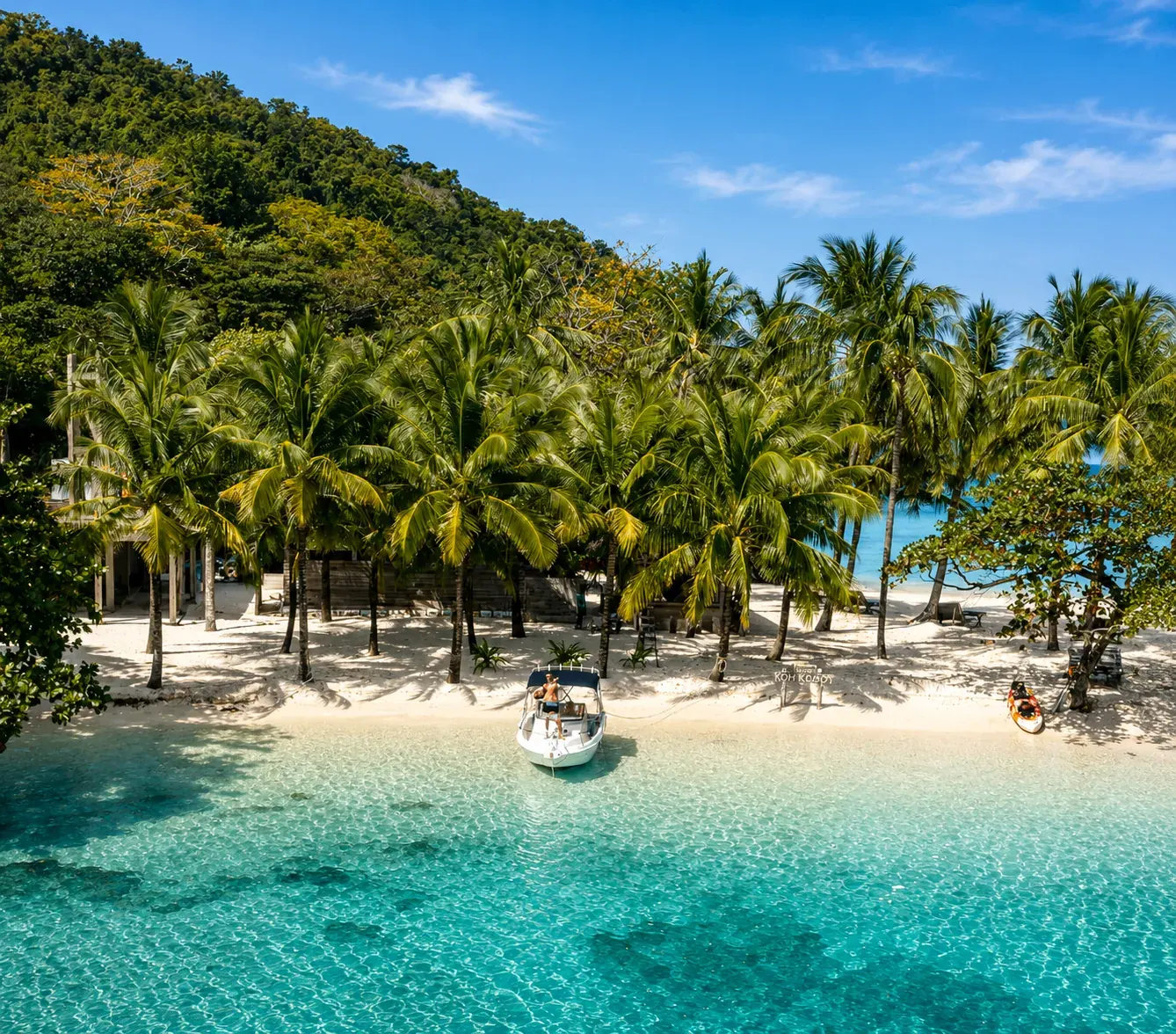 Speedboat moored on a palm-lined Koh Mak beach with clear turquoise water