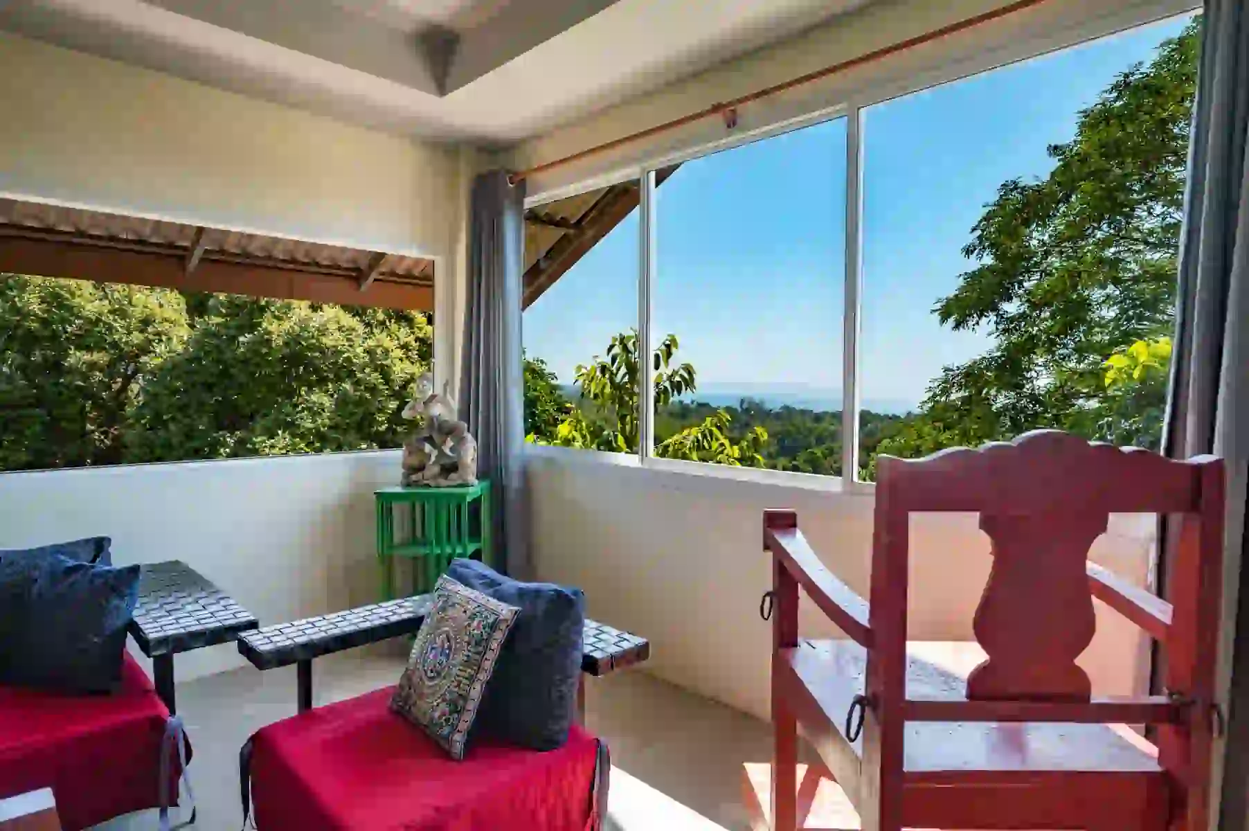 Penthouse balcony with red chairs, sea view and tropical greenery at Koh Mak Village