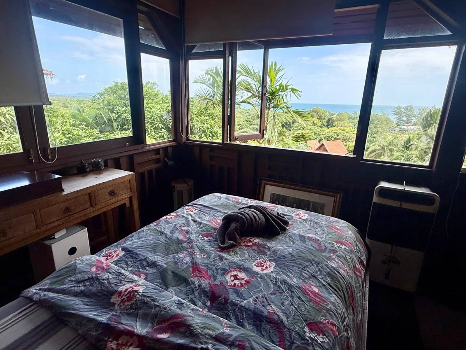 Bedroom of the Upstairs seaview suite with a floral-covered bed, wooden furniture and sea-view windows on Koh Mak