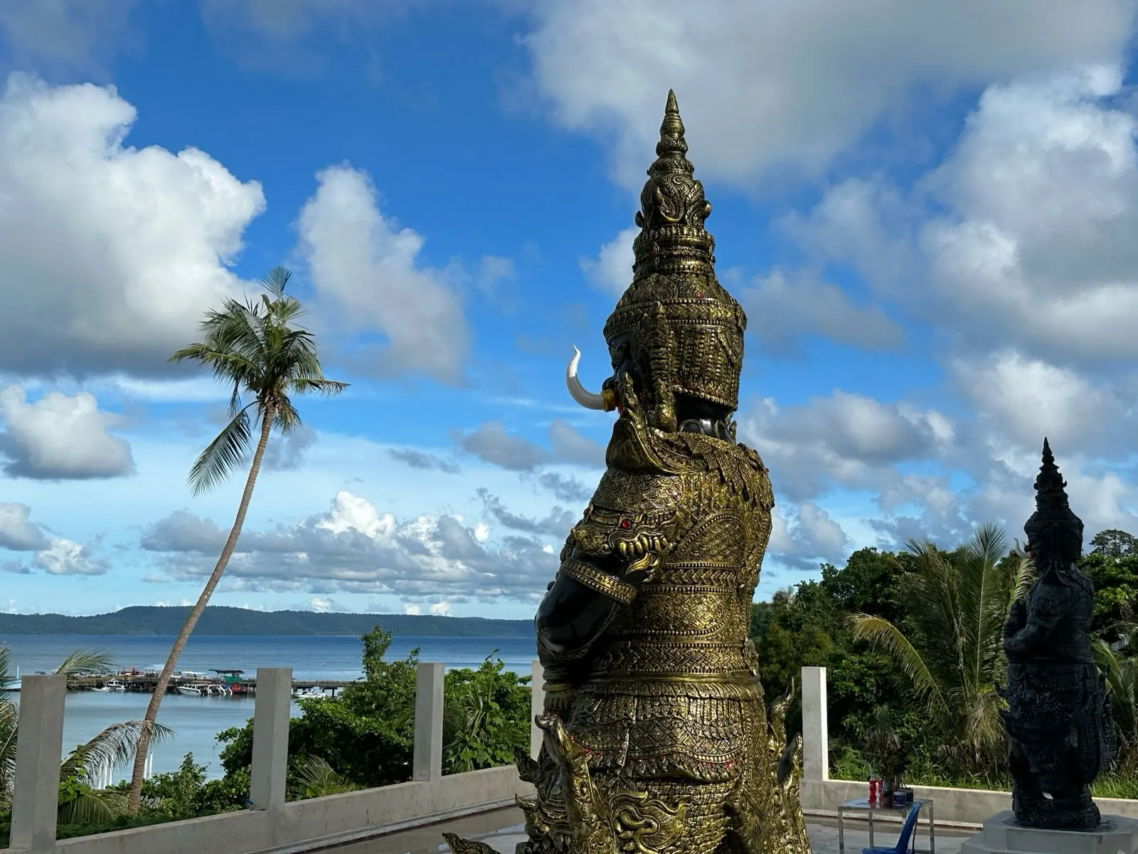 Golden Yaksha guardian statue overlooking Ao Nid pier and the sea at Wat Koh Mak